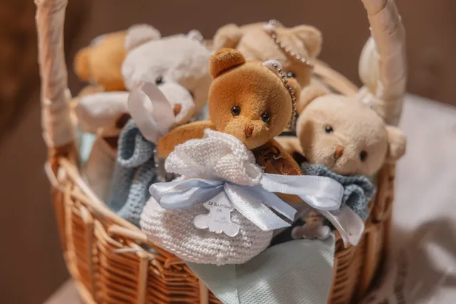 Des ours en peluche et des dragées en tulle bleu rangés dans un panier en osier