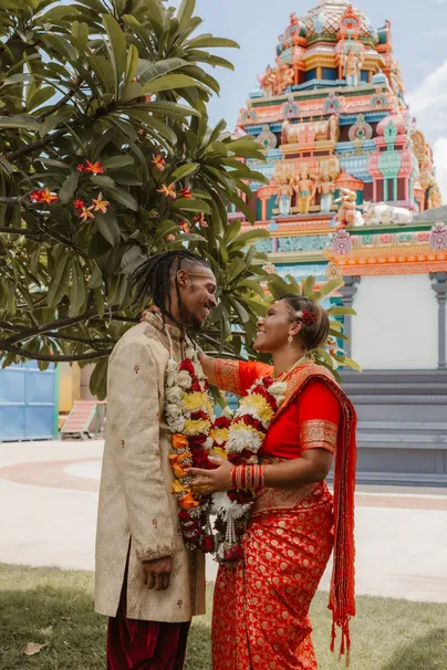 Les mariés échangent des guirlandes de fleurs devant un temple tamoul coloré