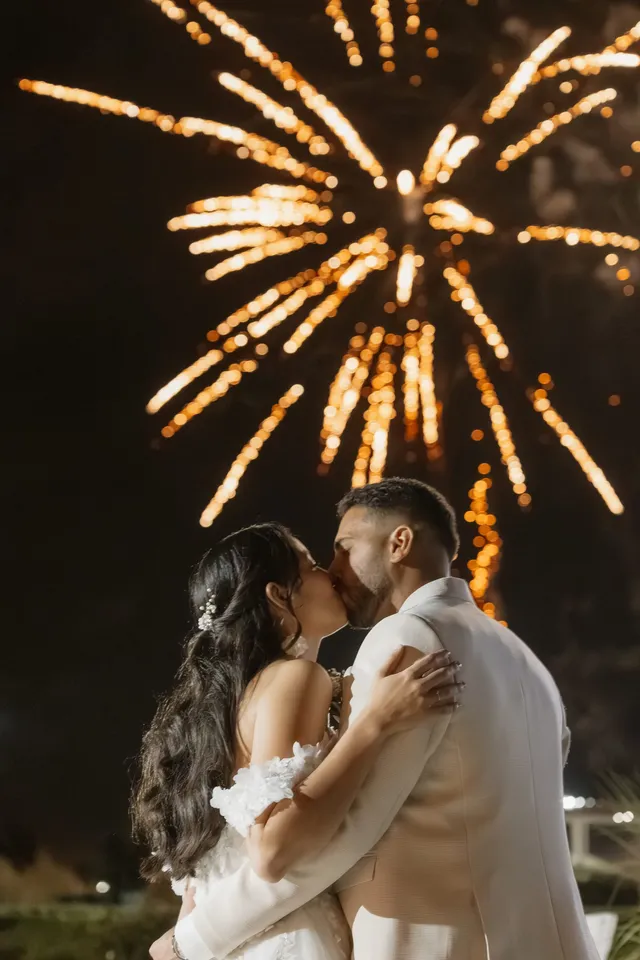 Les mariés s’embrassent sous un feu d’artifice, dans la nuit