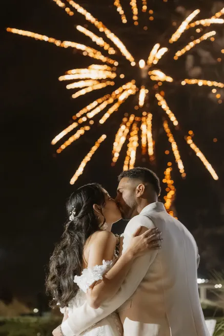 Les mariés s’embrassent sous un feu d’artifice, dans la nuit