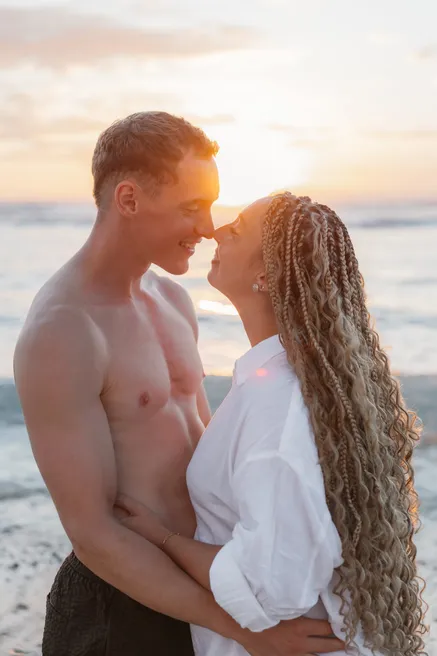 Un couple enlacé face au soleil couchant, sur la plage