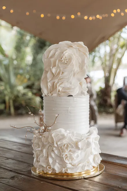 Pièce montée blanche à trois étages, décorée de fleurs en sucre