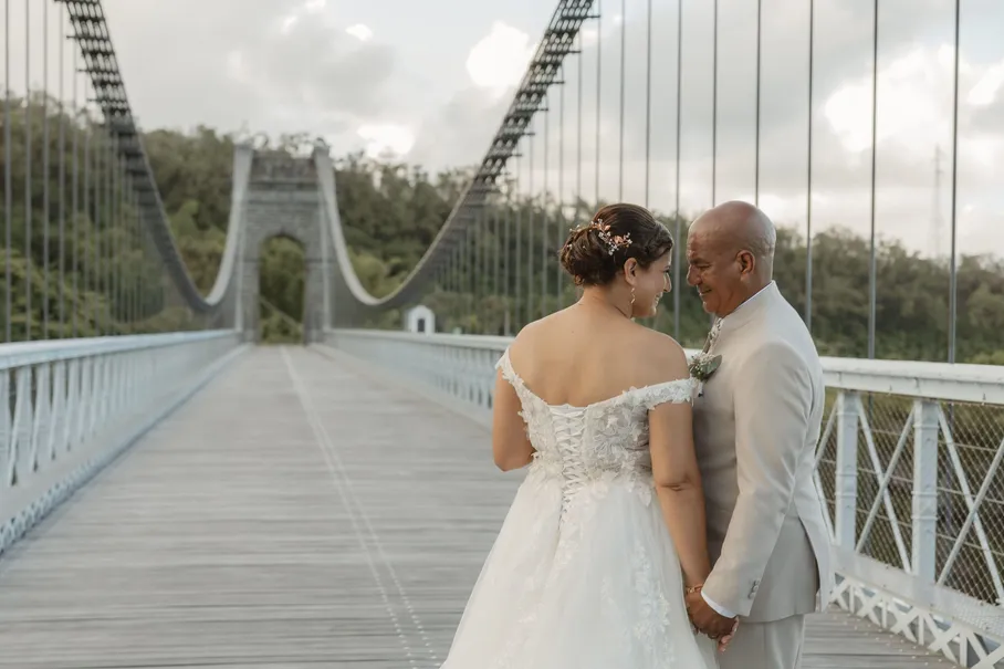 Les mariés se tiennent les mains au milieu d’un long pont suspendu