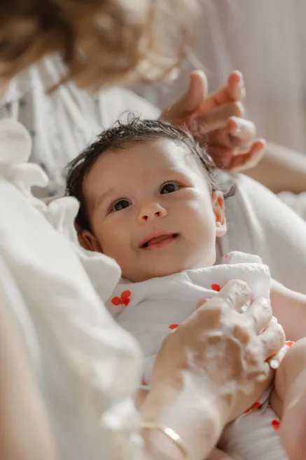 Le bébé sourit, allongé contre sa mère qui lui caresse les cheveux