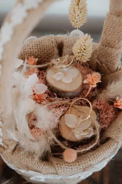 Porte-alliances en rondelles de bois dans une coupe de jute ornée de fleurs séchées