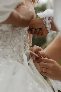 Une main lace le corset de la robe de mariée pendant les préparatifs