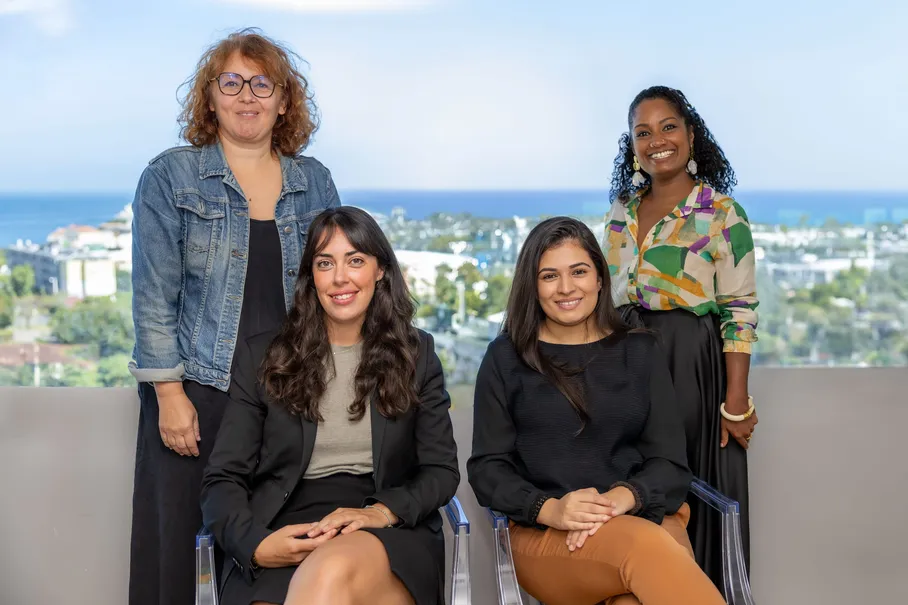 Quatre femmes posent ensemble, assises et debout, sur une terrasse face à la mer