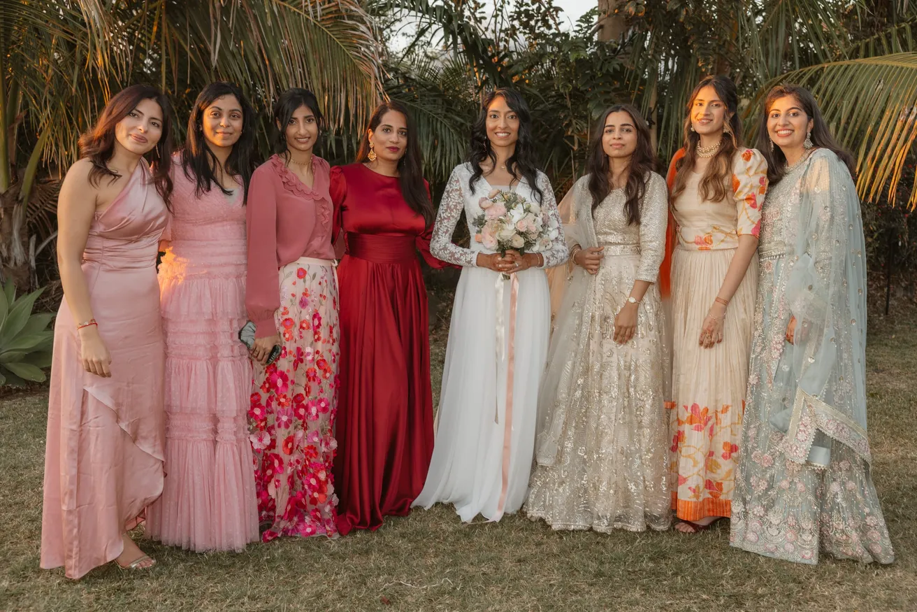 La mariée entourée de huit femmes en robes et tenues indiennes colorées dans un jardin