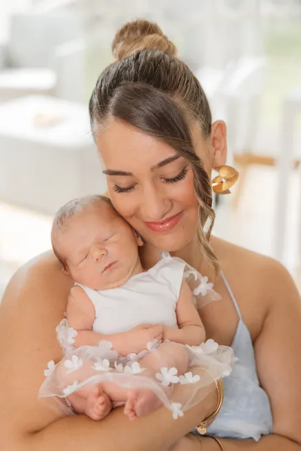 Une mère au chignon ferme les yeux, la joue contre le nouveau-né qu’elle berce