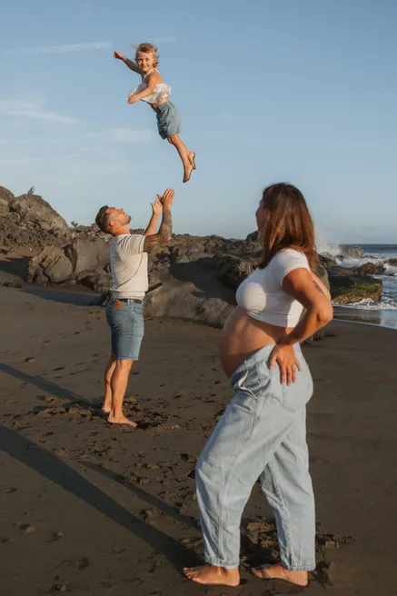Un père lance son enfant en l’air devant la future maman, sur la plage