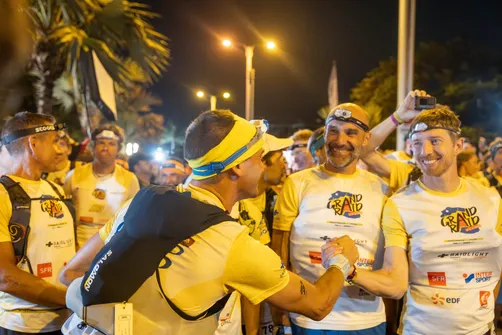De nuit, des coureurs de trail en tee-shirts jaunes s’encouragent sous les lampadaires avant le départ