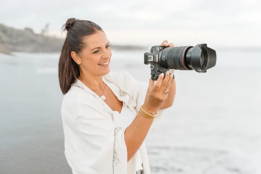 Lucile Boissé, souriante, l’appareil photo levé, au bord de la mer