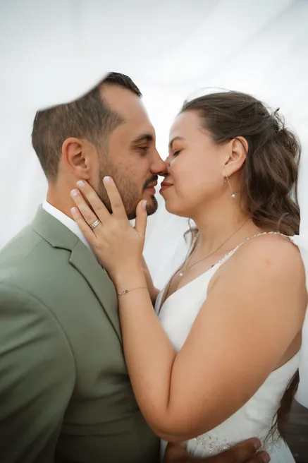 Les mariés nez contre nez, yeux fermés, la main de la mariée posée sur la joue du marié