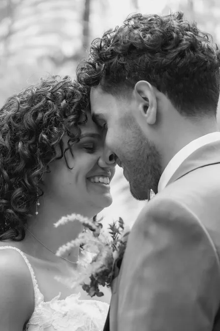 En noir et blanc, les mariés front contre front, les yeux baissés, souriants