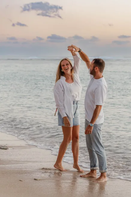 Un couple danse au bord de l’eau, il fait tourner sa compagne sous son bras levé