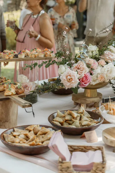 Un buffet de fête, bols de samoussas, canapés et bouquet de roses pâles